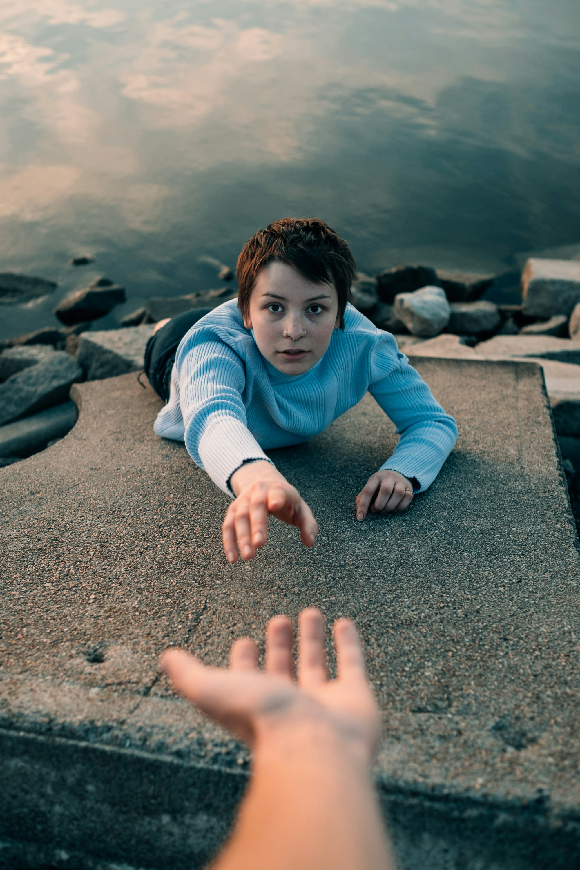 woman reaching hand above water during daytime photo